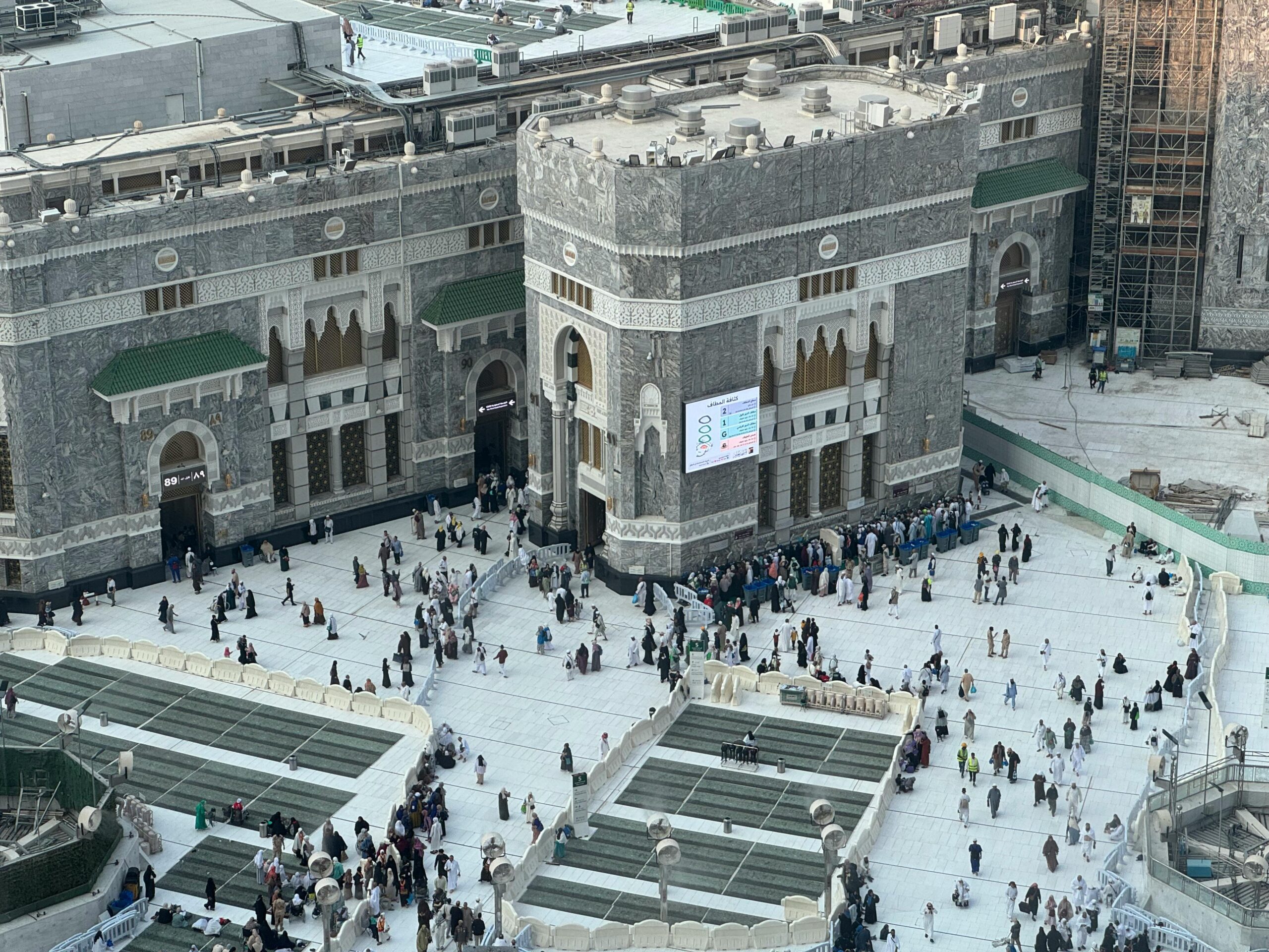 Aerial view of people around Masjid al-Haram in Mecca, showing its architecture and bustling atmosphere.